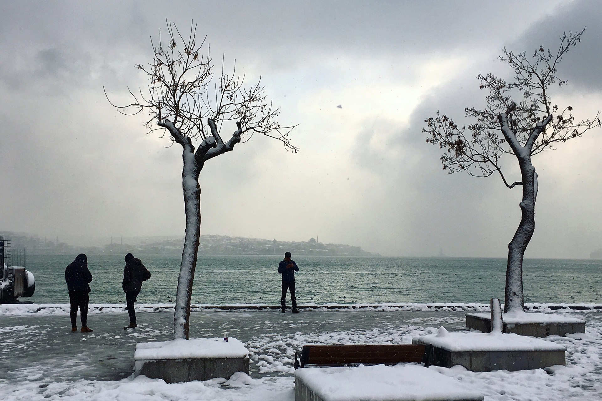 Kar yağmış İstanbul görüntüsü ve manzarayı seyreden 3 kişi.