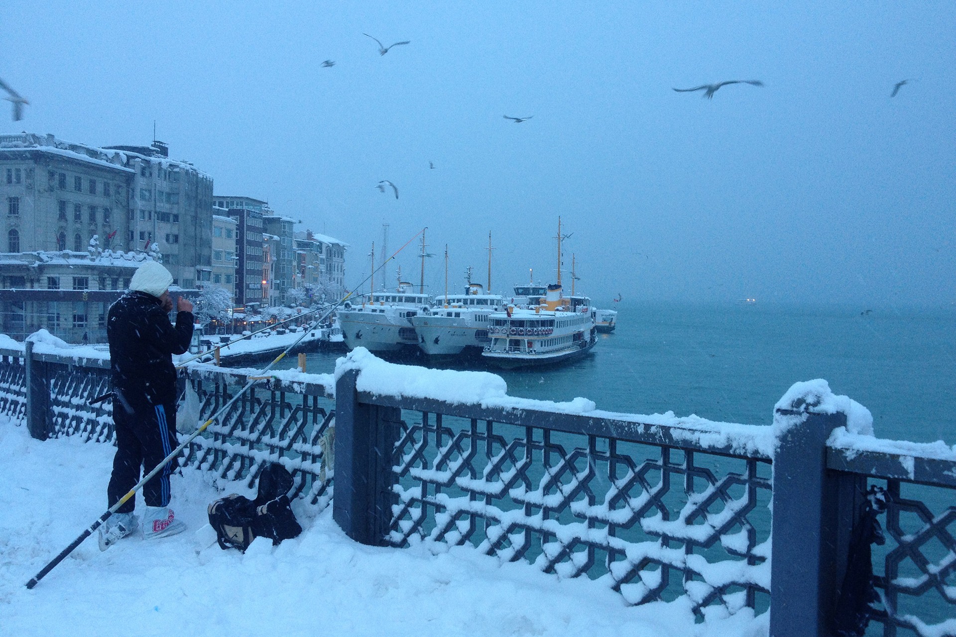 Kar altında Galata Köprüsü'nde balık tutan bir kişi.