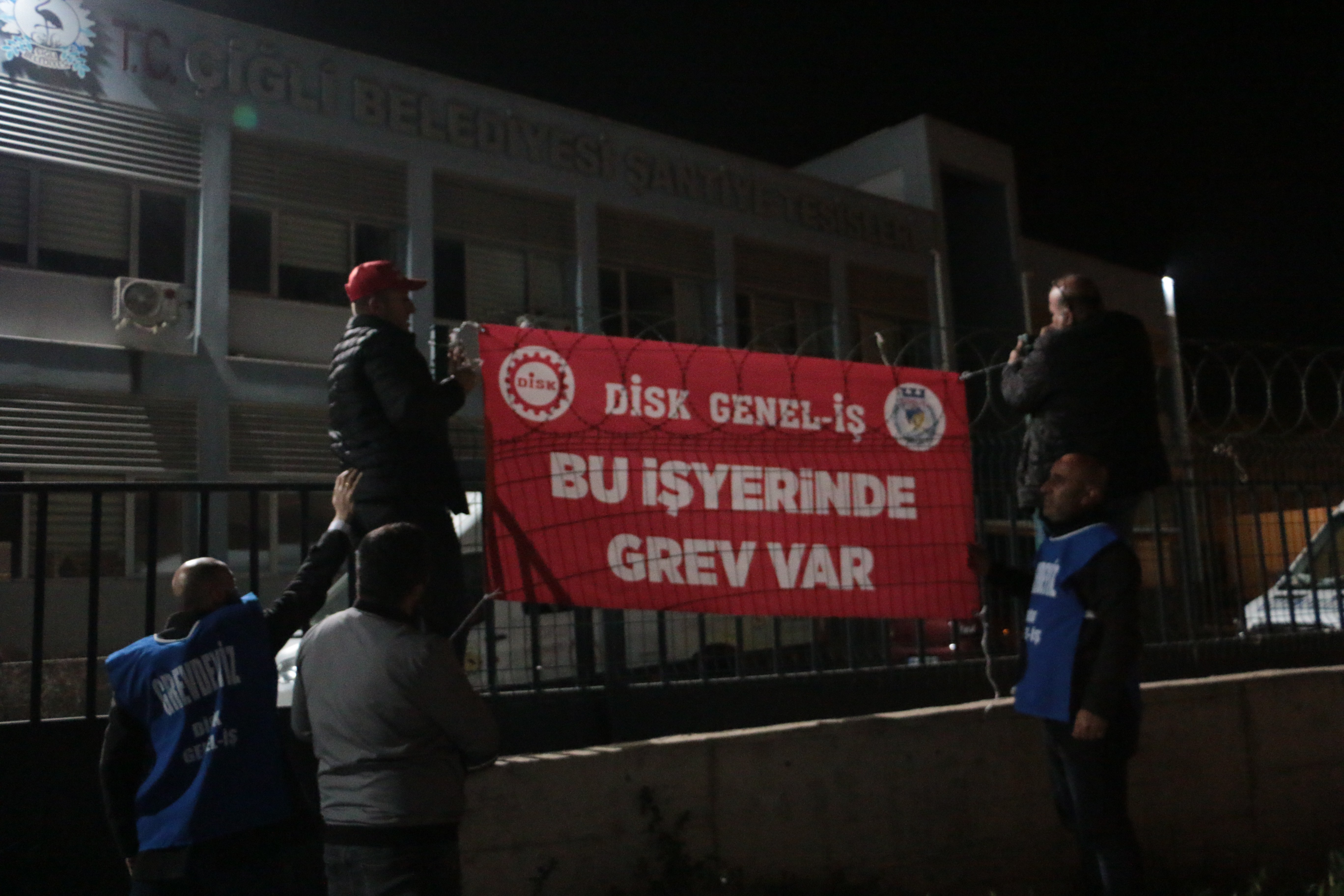 Çiğli Belediyesi işçileri greve pankartı önünde poz veriyor