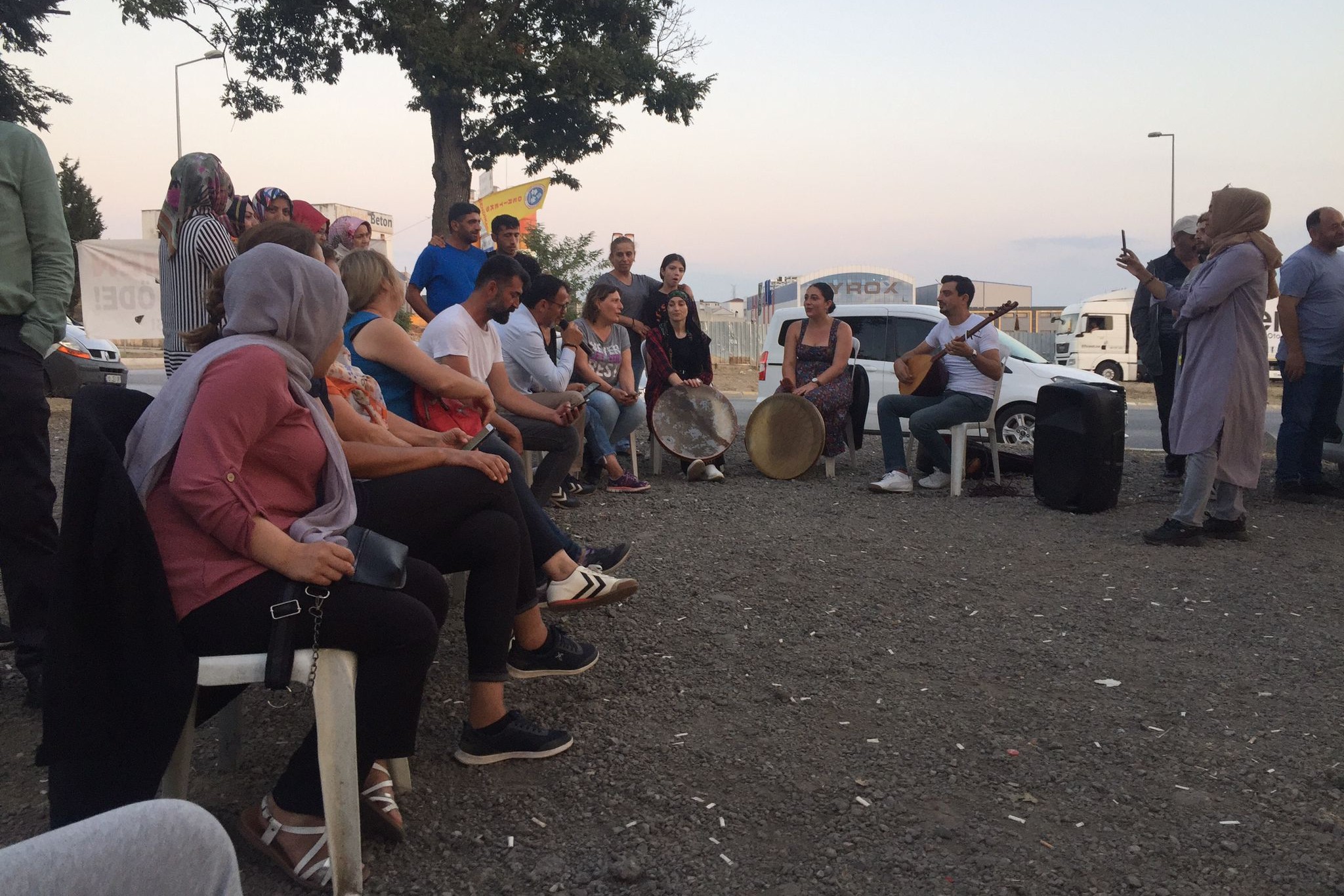 sandalyede oturan insanlar, ellerinde erbane ve bağlama olan 3 kişi 