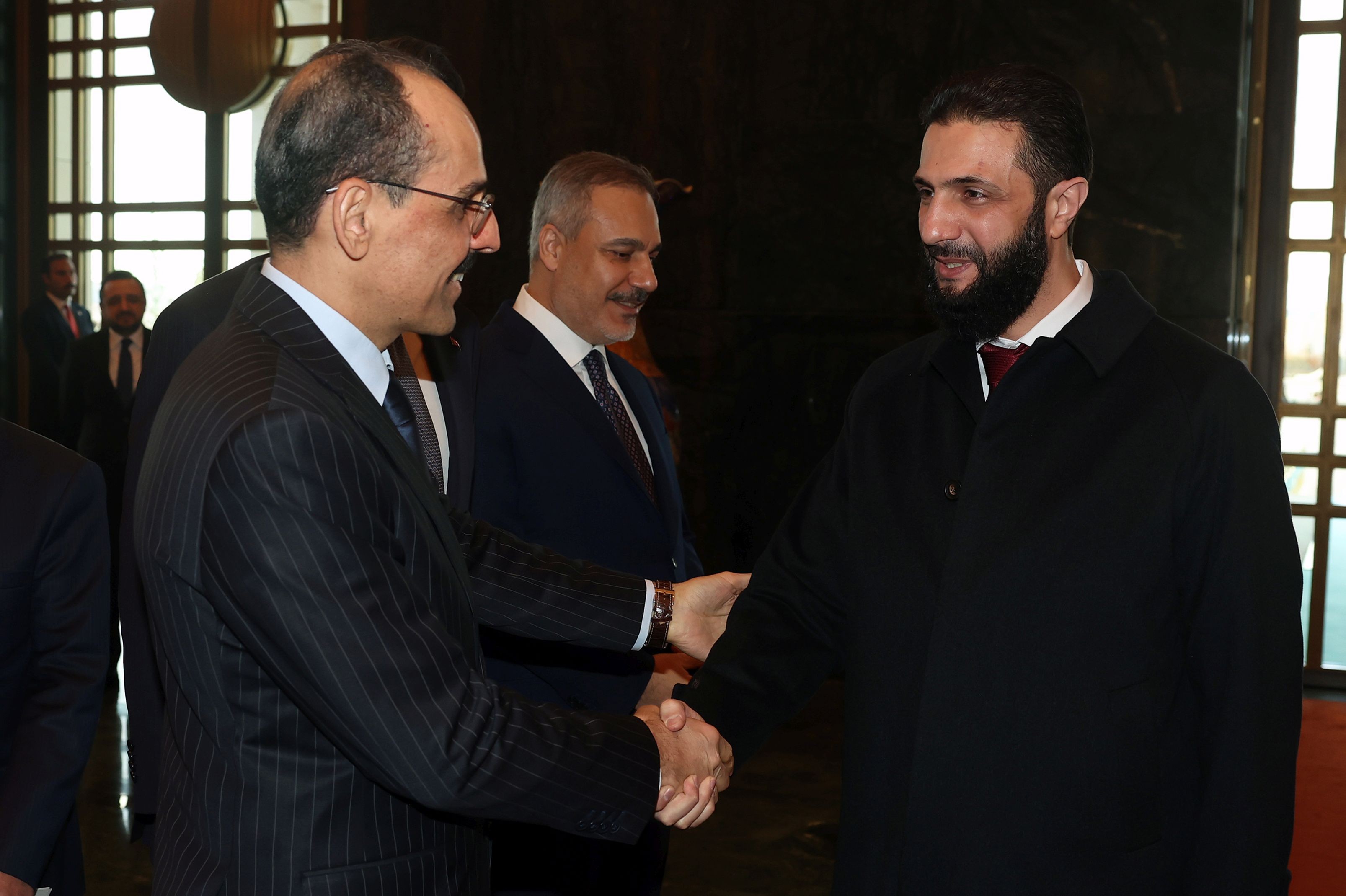 Colani ve İbrahim Kalın tokalaşıyor, arkada Hakan Fidan